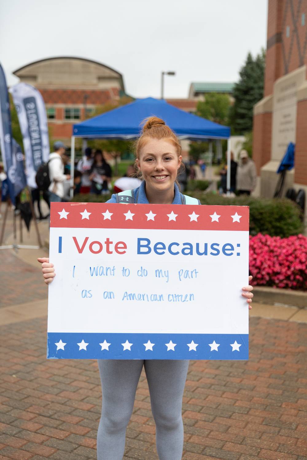 Student holding sign titled "I vote because: I want to do my part as an American citizen"